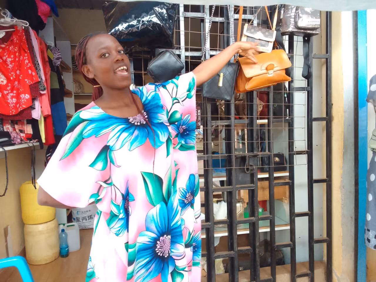 A retailer presenting a handbag beside her shop display.