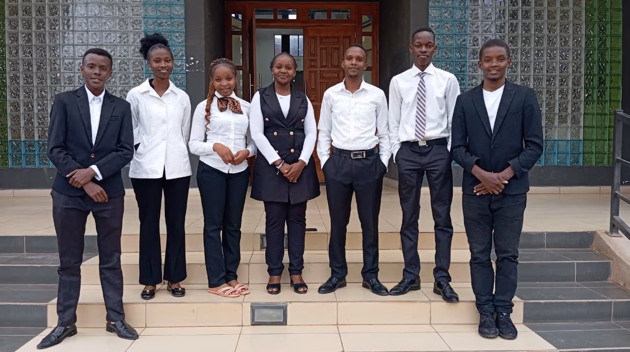 A formally dressed group of young people connected to AYCP outside a building in Kenya.